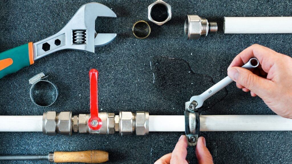 Plumber repairing a pipe valve with an adjustable wrench in Gilroy