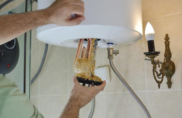 Technician removing mineral buildup from a water heater in Gilroy