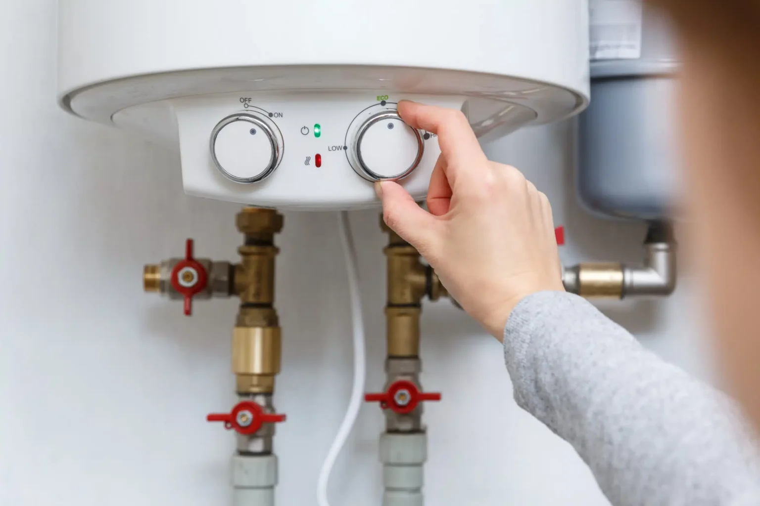 Homeowner adjusting the temperature controls on a water heater in Gilroy